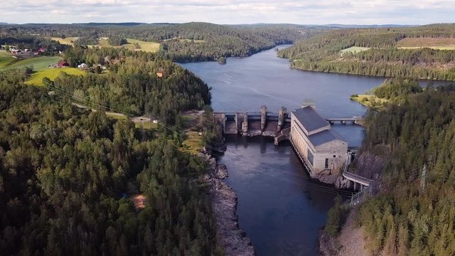 Aerial, hyperlapse, drone shot ,tilting towards the Solbersfossen hydropower plant dam, at Glomma river, on a sunny, summer day, in Spydeberg, Ostfold, Norway