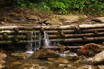 A small artificial waterfall in a forest of logs