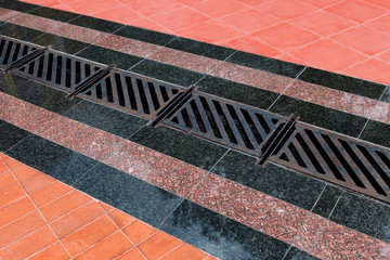 Pedestrian covering, lined with granite tiles with metal drainage grate.
