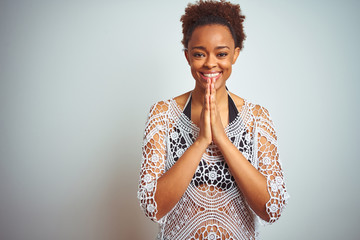 Young african american woman with afro hair wearing a bikini over white isolated background praying with hands together asking for forgiveness smiling confident.