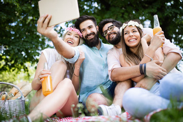 Happy friends in the park having picnic on a sunny day.