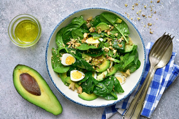Green vegetable salad with baby spinach, avocado, walnut and egg in a bowl. Top view with copy space.