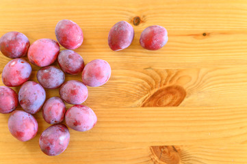 Several fresh ripe plums on wooden background