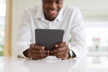 Close up of african business man using touchpad tablet, working sitting on a desk smiling