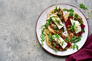 Healthy toasts with beetroot, feta cheese, nuts and arugula.Top view with copy space.