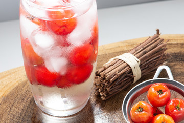 Acerola juice and Acerola fruit in a sieve and wooden background