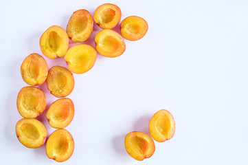 Several fresh ripe plums cut in half on white background