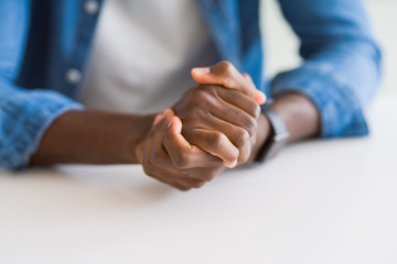 Fototapeta premium Close up of crossed hands of african man over table