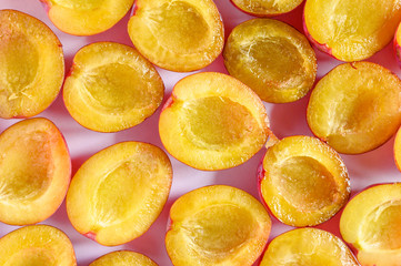 The background of a several fresh ripe plums cut in half