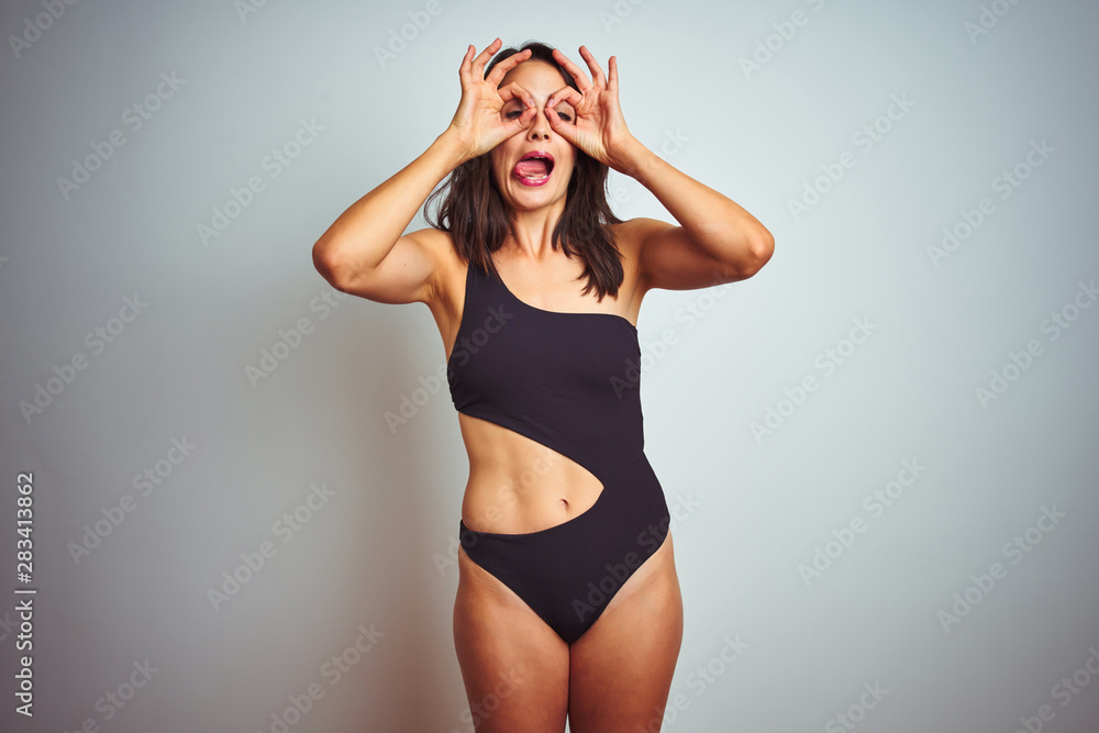 Wall mural beautiful woman wearing bikini swimwear over white isolated background doing ok gesture like binocul