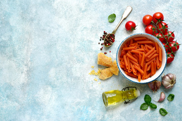 Traditional ingredients of italian cuisine : pasta penne, tomato, garlic, olive oil, parmesan cheese and basil. Top view with copy space.