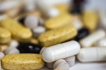 Fototapeta na wymiar Piles of pills and capsule on white background. Selective focus