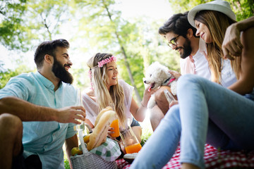 Happy friends in the park having picnic on a sunny day.