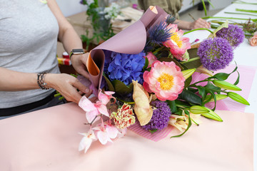 Female florist explain to students how to create bouquet at workplace. Floristics workshop.  Making...