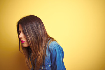 Young beautiful woman standing over yellow isolated background Suffering of backache, touching back with hand, muscular pain