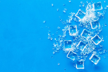 Frozen water in ice cubes on blue bar table top view mock up