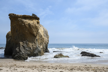 Fototapeta na wymiar ocean waves on rock in El Matador Beach, Malibu with a sunny blue day in summer time