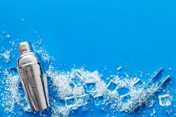 Frozen water in ice cubes and shaker on white bar table top view copyspace