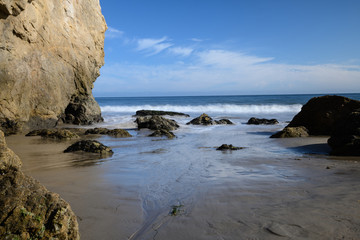 Fototapeta na wymiar ocean waves on rock in El Matador Beach, Malibu with a sunny blue day in summer time