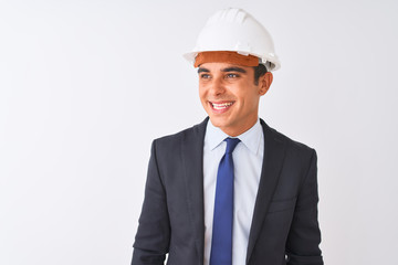 Young handsome architect man wearing suit and helmet over isolated white background looking away to side with smile on face, natural expression. Laughing confident.