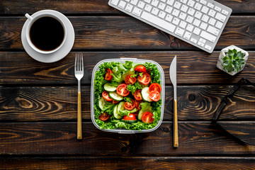 to-go box with salad, coffee for lunch in office and keyboard on wooden background top view