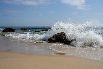 ocean waves on rock in El Matador Beach, Malibu with a sunny blue day in summer time