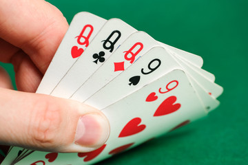 Hand holds a combination in poker - full house on a green background.