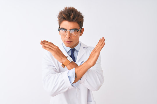 Young handsome sciencist man wearing glasses and coat over isolated white background Rejection expression crossing arms doing negative sign, angry face