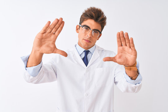Young handsome sciencist man wearing glasses and coat over isolated white background doing frame using hands palms and fingers, camera perspective