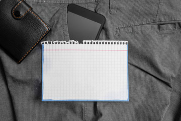 Smartphone device inside trousers front pocket with wallet and note paper