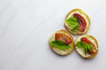 Tasty bruschettas with sun-dried tomatoes on light background