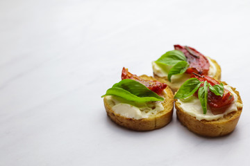 Tasty bruschettas with sun-dried tomatoes on light background