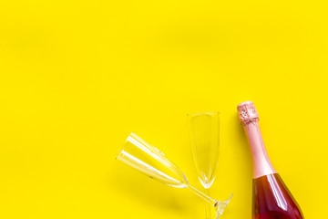 Champagne bottle with glasses for celebration on yellow background top view mock up