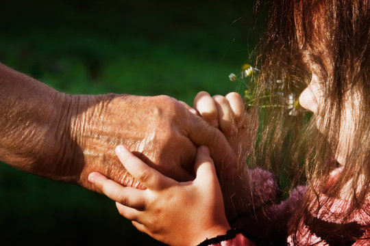 An old grandmother gives a child a sniff of a flower