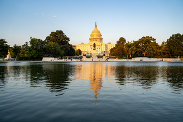 United States Capitol building at dusk sunset during a summer day, glowing from sunshine, with reflecting pond