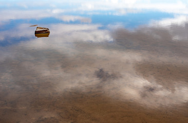Minimalist image of a rock sitting in still water with sky reflected