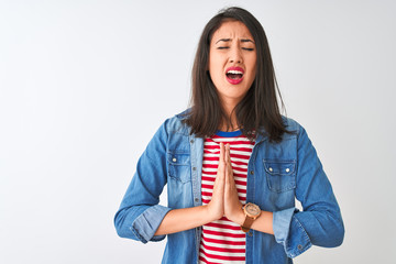 Young chinese woman wearing striped t-shirt and denim shirt over isolated white background begging...
