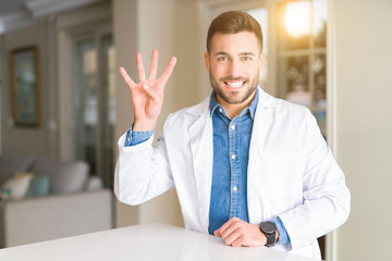Young handsome doctor man at the clinic showing and pointing up with fingers number four while smiling confident and happy.