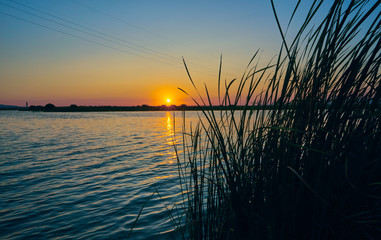 Sunset in a landscape with lake, trees and light towers. Extremadura. Spain