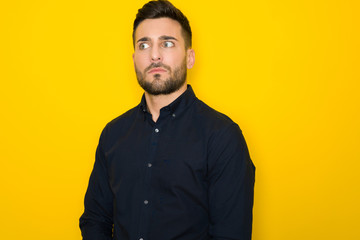 Obraz premium Young handsome man possing and modeling over yellow isolated background