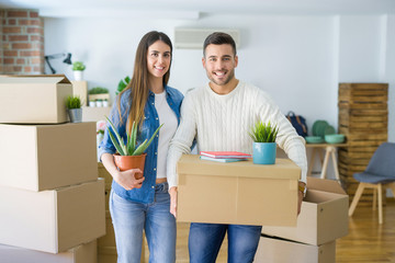 Beautiful young couple moving to a new house, smiling happy holding cardboard boxes at new apartment