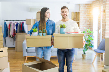 Fototapeta na wymiar Young couple moving to a new home, smiling happy holding cardboard boxes at new apartment