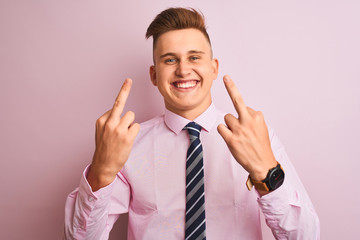 Young handsome businessman wearing shirt and tie standing over isolated pink background Showing middle finger doing fuck you bad expression, provocation and rude attitude. Screaming excited