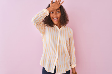 Young brazilian woman wearing striped shirt standing over isolated pink background surprised with...