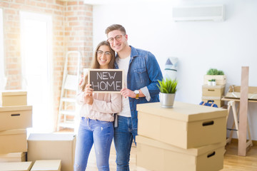 Fototapeta na wymiar Beautiful young couple hugging in love and holding blackboard moving to a new home, smiling happy for new apartment