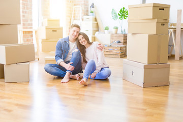 Fototapeta na wymiar Young beautiful couple relaxing sitting on the floor around cardboard boxes at home, smiling happy moving to a new house