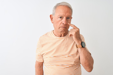 Senior grey-haired man wearing striped t-shirt standing over isolated white background Pointing to the eye watching you gesture, suspicious expression