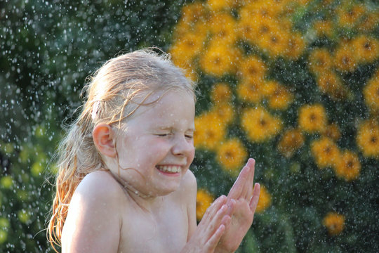 Erfrischende Dusche mit dem Rasensprenger im Garten
