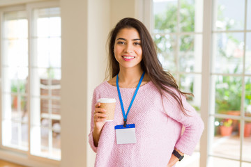 Young beautiful business woman wearing an id card drinking a cup of coffee