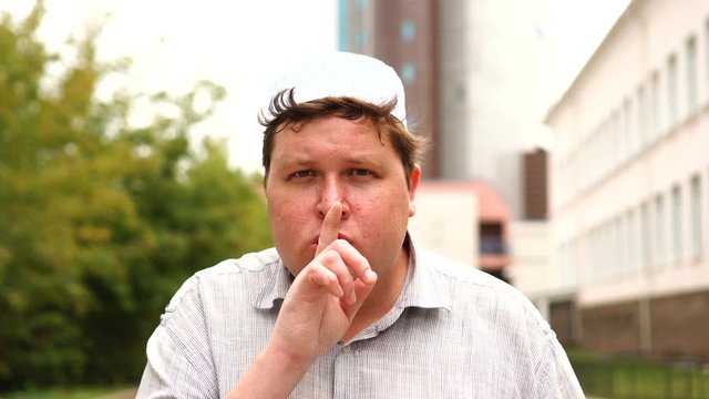 Muslim man making a shushing gesture raising his finger to his lips in a seductive gesture as he asks for silence